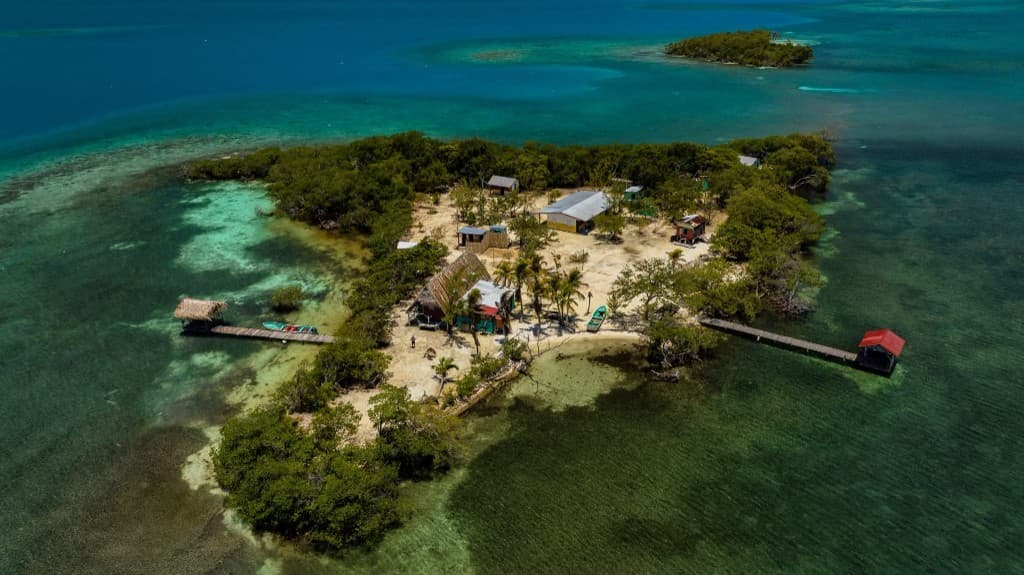 Aerial view of Hawk Caye Lodge surrounded by turquoise water and coral reef